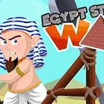 Egy egyiptomi ruhás, harcos kinézetű karakter áll egy csúzli szerkezet mellett, háttérben sivatagi tájjal és két fából készült állvánnyal, felül Egypt Stone War szöveggel