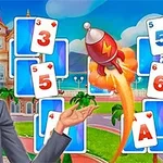 Egy szőke hajú nő kártyalapokkal és egy rakétával a háttérben, színes tájjal