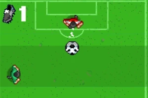 Zöld futballpálya közepén egy focilabda, bal oldalon és a kapunál két játékos pixelgrafikával