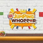 Fehér téglafal Burger King logóval és Jumping Whopper felirattal, alatta egy asztalon Whopper szendviccsel