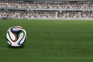 Színes mintázatú focilabda egy stadion zöld füvén