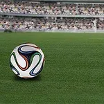 Színes mintázatú focilabda egy stadion zöld füvén