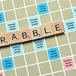 A kép egy scrabble táblát mutat, amelyen a SCRABBLE szó van kirakva fa betűlapkákkal