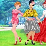 Három fiatal nő színes ruhákban pózol egy parkos háttér előtt